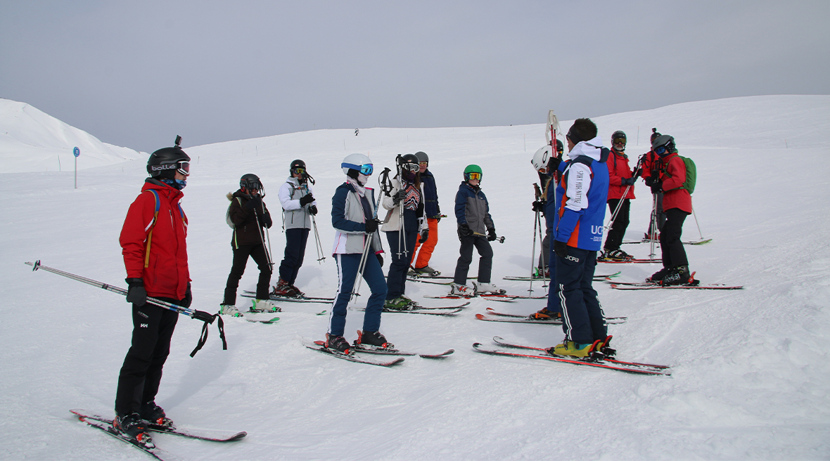 A group of skiers listen as their instructor tells them what to do